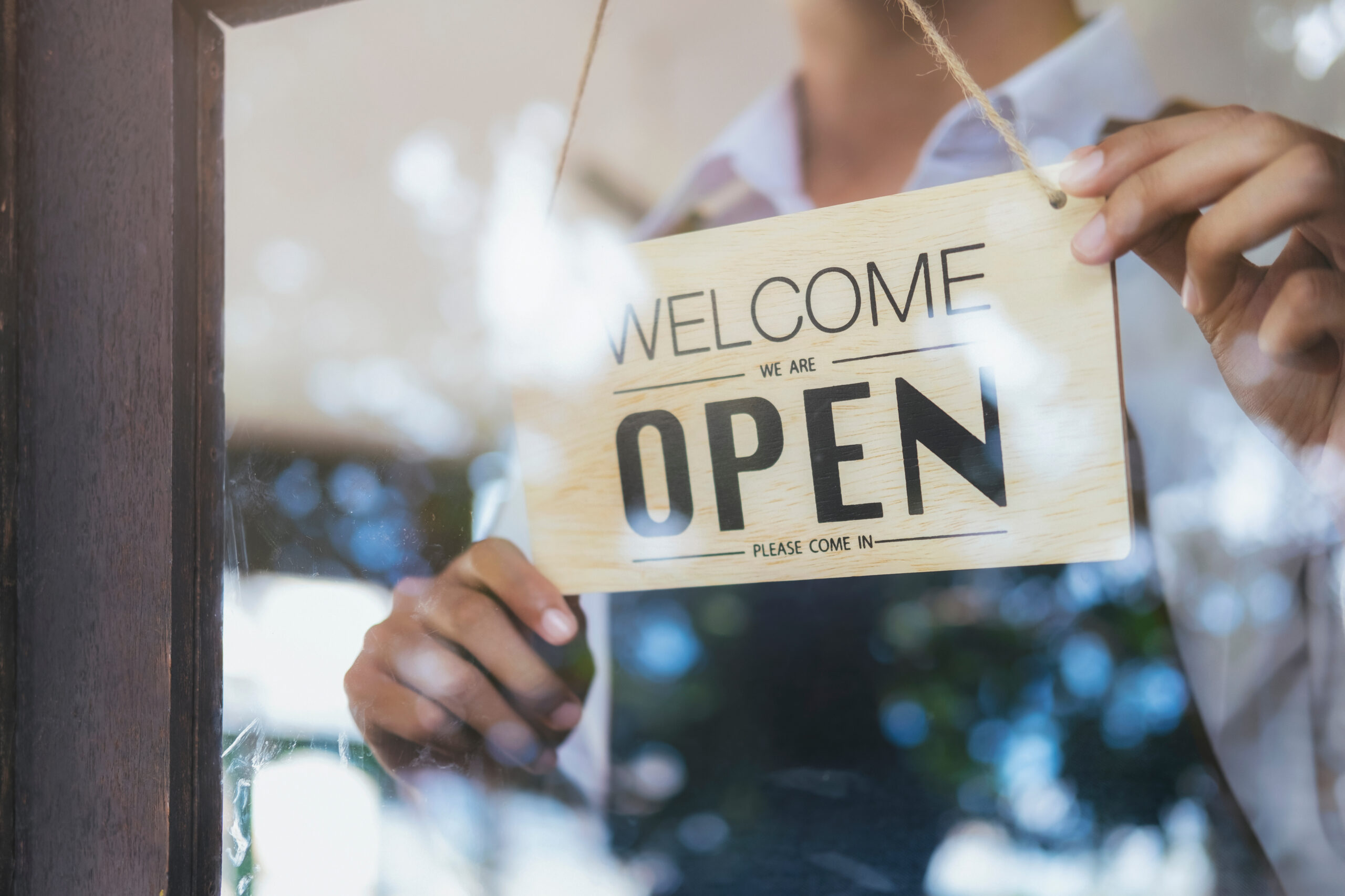 Young startup coffee cafe owener open and welcome customer. Wooden blocks showing the building blocks of a successful business. Hand Me The Key provides small business coaching to help you thrive.