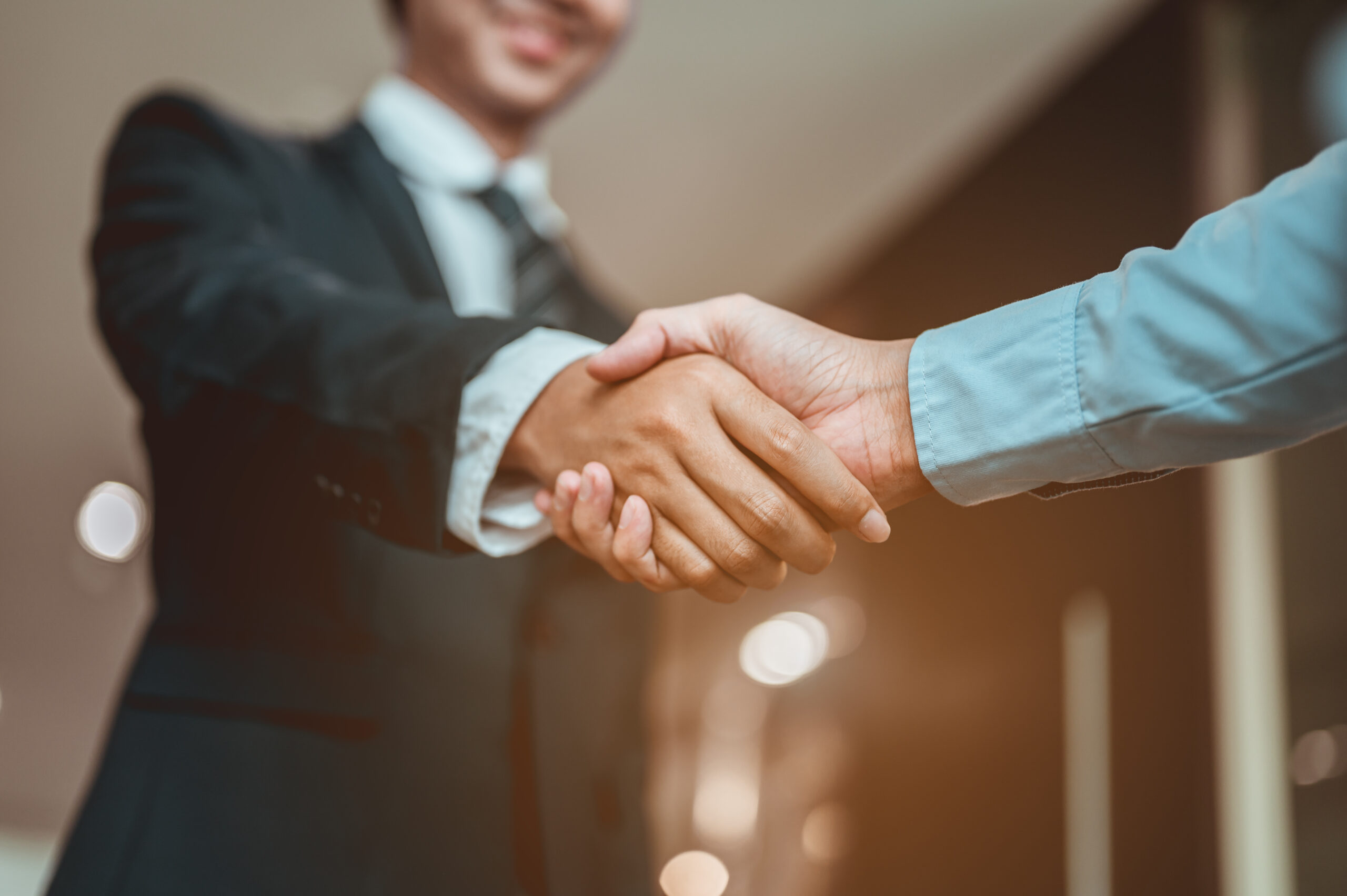 Businessman shake hands and get to know each other before they start talking about business.Bussiness,working, success concept Wooden blocks showing the building blocks of a successful business. Hand Me The Key provides small business coaching to help you thrive.